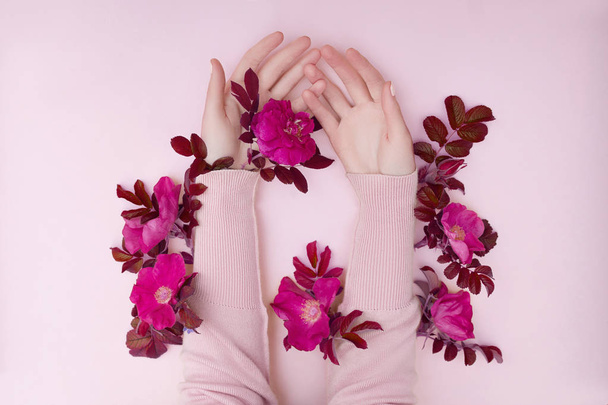 Hand with pink flowers and petals lying on a paper background. C - Foto, Imagen