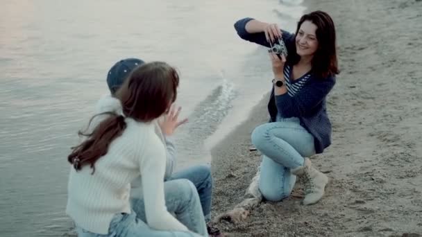giovane madre fotografa i bambini su una macchina fotografica. la famiglia trascorre del tempo insieme in riva al mare
. - Filmati, video