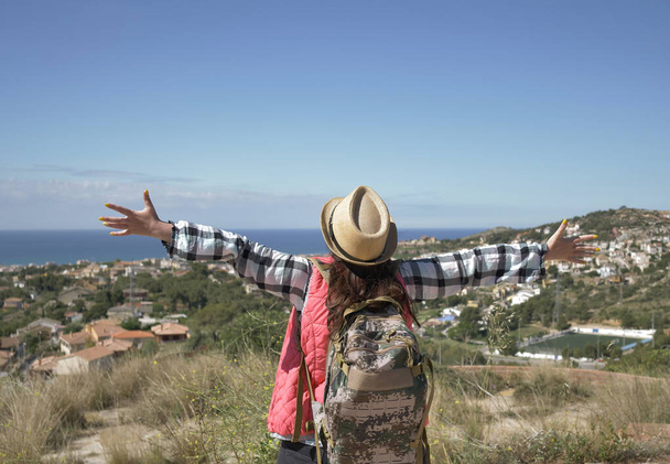Молода жінка турист з рюкзаком піднімає руки в небо на вершині гори, копійка
 - Фото, зображення