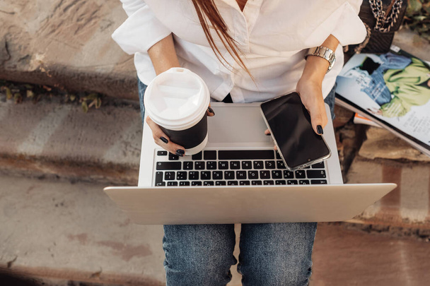 Ritratto di una ragazza alla moda vestita con jeans e camicia bianca che tiene il computer portatile, lavoratore freelance, donna d'affari, concetto di potere della donna
 - Foto, immagini
