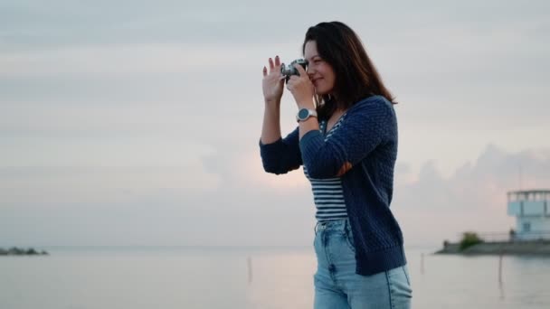giovane donna scatta foto su una macchina fotografica d'epoca in riva al mare. ritratto di una ragazza con una macchina fotografica retrò
 - Filmati, video