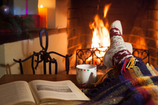 Man and woman in warm socks near the fireplace. Cup with a hot drink. Heart. - Valokuva, kuva