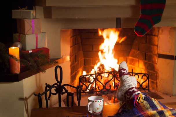 Man and woman in warm socks near the fireplace. Cup with a hot drink. Heart. - Foto, Imagen