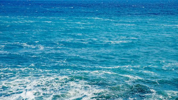 Голубая изумрудная морская вода с большими камнями пляжа. Скалистый берег прозрачного бирюзового дна Мальты
 - Фото, изображение