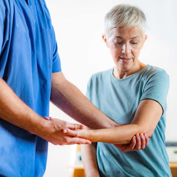 Therapeutin überprüft Arm von Seniorin in Physiotherapiepraxis  - Foto, Bild