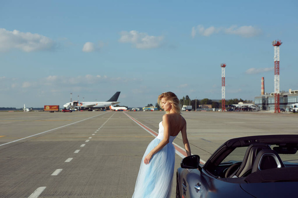 Kyiv, Ukraine - September 2, 2017: The elegant blonde beautiful woman posing near Mercedes Benz AMG GT 50 Edition sports car in airport. A new 2017 supercar designed to celebrate the 50th anniversary - 写真・画像