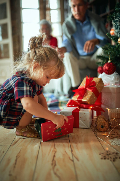 dziewczyna otwarty prezent przed dekorowane choinki - Zdjęcie, obraz