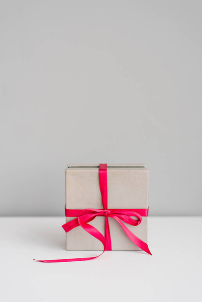 graue Geschenkschachtel, gebunden mit einem lila Band auf grauem Hintergrund. Kopierraum - Foto, Bild