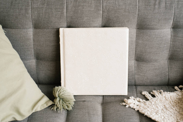 Λευκό βιβλίο φωτογραφιών γάμου σε δερμάτινο κάλυμμα με σχέδιο δαντέλας σε γκρι φόντο υφάσματος - Φωτογραφία, εικόνα