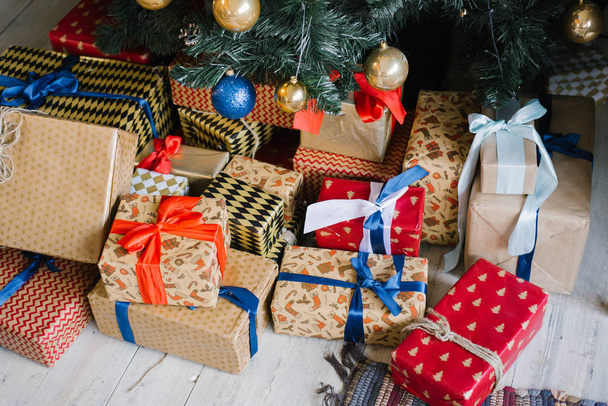 Φωτεινά κουτιά δώρων σε συσκευασία Χριστουγέννων βρίσκονται κάτω από το χριστουγεννιάτικο δέντρο - Φωτογραφία, εικόνα
