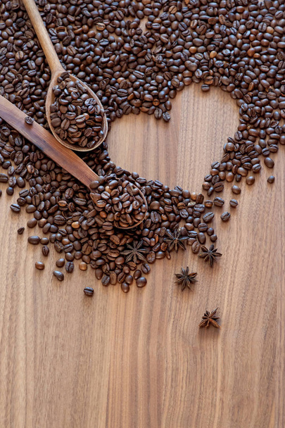 Ziarna kawy rozlane na drewnianym stole w kształcie serca z przyprawami  - Zdjęcie, obraz