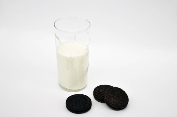 glas melk en koekjes op witte achtergrond - Foto, afbeelding