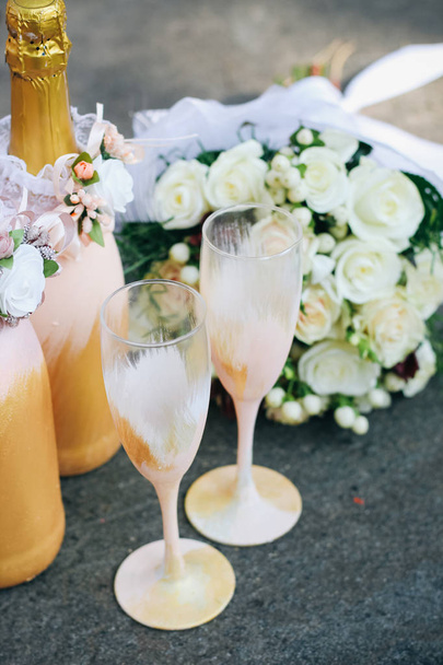 Decorazione nuziale di bottiglie di champagne e bicchieri nei toni dell'oro
 - Foto, immagini