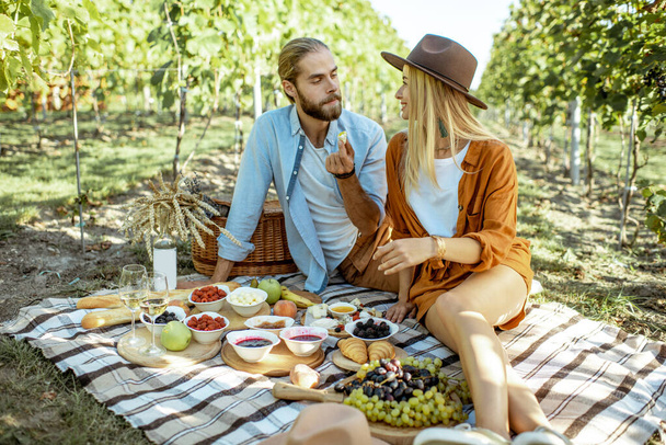 A fiatal pár a szőlőskertben reggelizik. - Fotó, kép