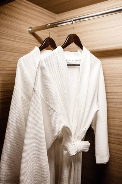 zwei weiße Duschkleider im Schrank aufgehängt - Foto, Bild