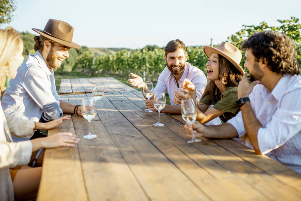 Freunde trinken Wein am Esstisch im Weinberg - Foto, Bild
