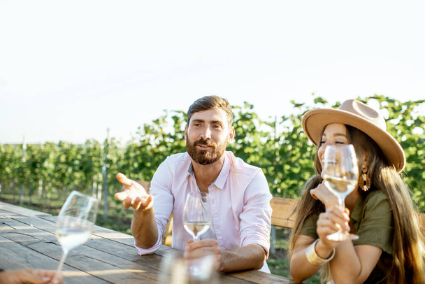 Друзья пьют вино за обеденным столом на винограднике
 - Фото, изображение