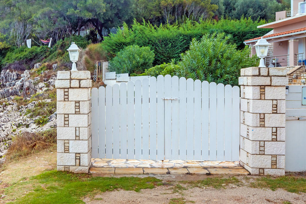Kaunis valkoinen portti merenpinnan yläpuolella. Sisäänkäynti sisäpihalle. Korfu, Kreikka
.  - Valokuva, kuva