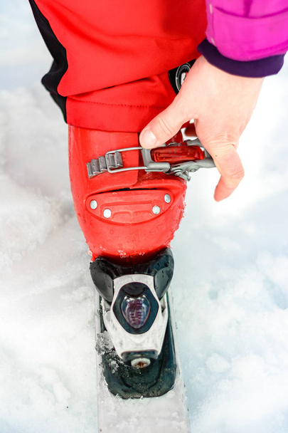 Esquiador en traje de esquí rojo y botas de esquí rojo y esquís blancos, primer plano
. - Foto, Imagen