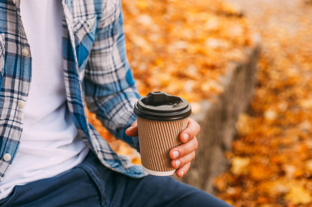 Paper cup of coffee in man hand in the autumn park - Foto, immagini