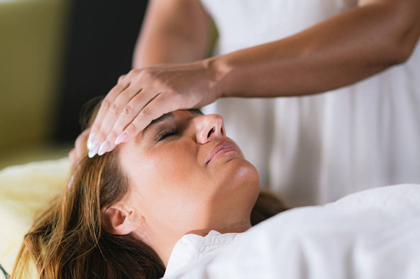 Terapeut Reiki přenáší energii. Mírumilovná žena leží se zavřenýma očima.  - Fotografie, Obrázek