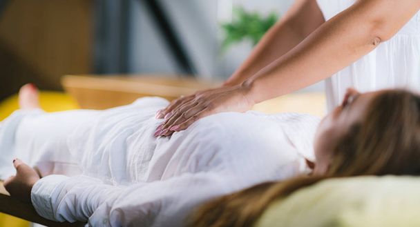 Female Therapist Performing Reiki Therapy Treatment. Hands Over Woman's Stomach. Alternative Therapy Concept, Stress Reduction and Relaxation.   - Photo, Image