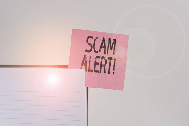 Text sign showing Scam Alert. Conceptual photo fraudulently obtain money from victim by persuading him Upper view lined hard cover note book sticky note inserted clear background. - Photo, Image