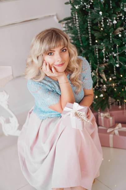 Lovely young woman with elegant style sitting indoor with pink Christmas present - Фото, зображення