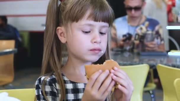 Mooi kind meisje eten Fast Food in restaurant. - Video