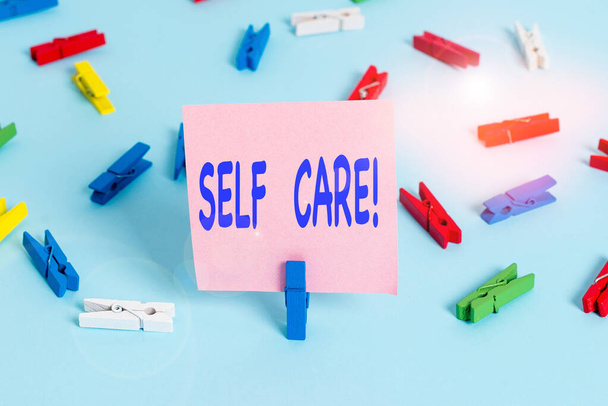 Text sign showing Self Care. Conceptual photo practice of taking action to preserve or improve ones own health Colored clothespin papers empty reminder blue floor background office pin. - Photo, Image