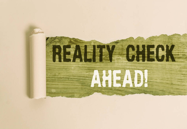 Writing note showing Reality Check Ahead. Business photo showcasing makes them recognize truth about situations or difficulties Cardboard which is torn placed above a wooden classic table. - Photo, Image