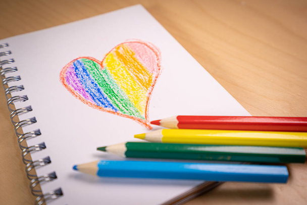 Heart with the colors of the LGTBI or GLBT flag on a blank notebook with rainbow pens - Zdjęcie, obraz