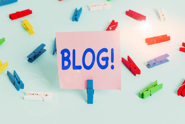 Blogot mutató szöveges jel. Fogalmi fotó rendszeresen frissített weboldal weboldal által működtetett egyéni színes ruhacsap papírok üres emlékeztető kék padló háttér iroda pin. - Fotó, kép