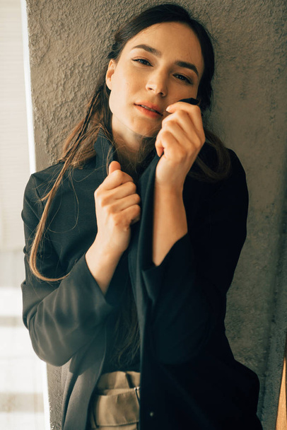 attraente bruna donna in stile moda vestiti posa vicino alla parete
  - Foto, immagini