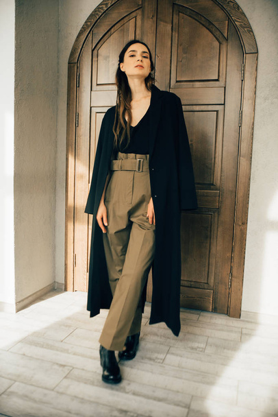 attractive brunette woman in fashion style clothes posing near wooden door  - Foto, Bild