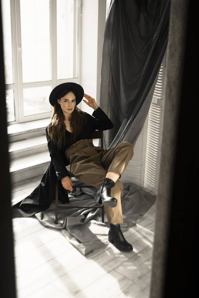魅力的なブルネットの女性ファッションスタイルの服で椅子に座ってスタジオでポーズ  - 写真・画像