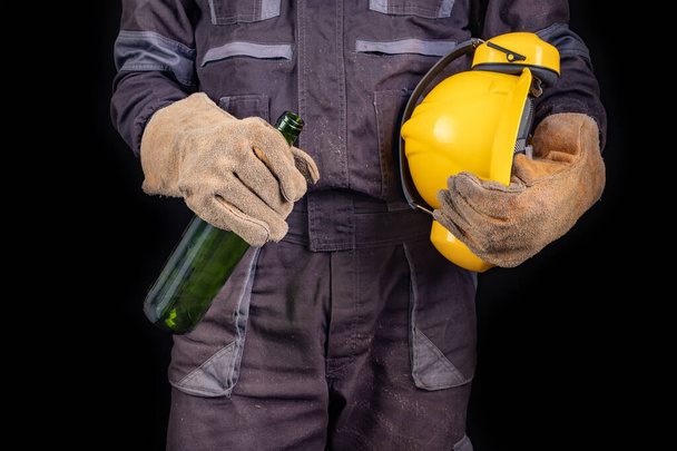 Bir şişe şarapla birlikte güvenlik elbisesi giymiş bir işçi.. - Fotoğraf, Görsel