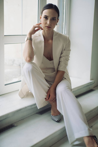 divat stílus nő fehér ruhák pózol ablak közelében stúdió  - Fotó, kép