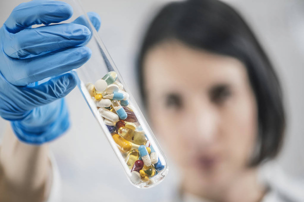 Pharmaforschung. Arzt hält Laborglasreagenzglas in der Hand, gefüllt mit bunten Pillen.  - Foto, Bild