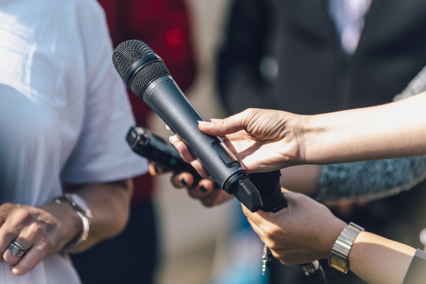 Dziennikarze trzymający mikrofon i dyktafon, przeprowadzający wywiad z mówczynią. - Zdjęcie, obraz
