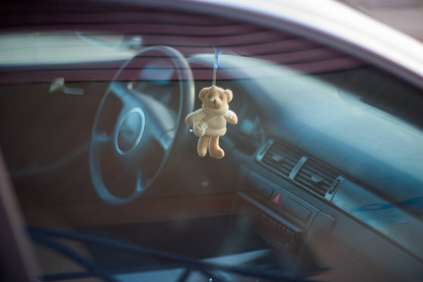 Teddy urso no carro, brinquedo macio pendurado no espelho retrovisor
 - Foto, Imagem