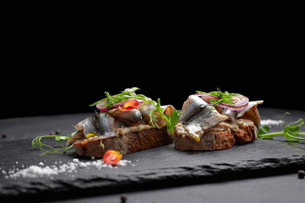 Сэндвичи с тюлем из рыбы на черном фоне. Брюскетты
 - Фото, изображение