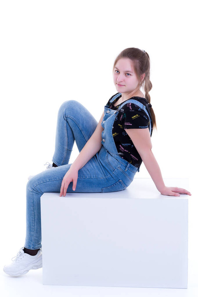 Teenage girl posing studio on a white cube. - Zdjęcie, obraz