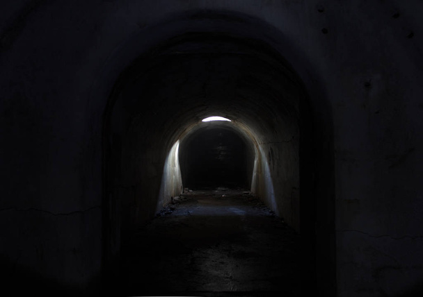 Een donkere ondergrondse doorgang in Fort Pospelova, verlicht door de zon door een luik in het plafond. - Foto, afbeelding