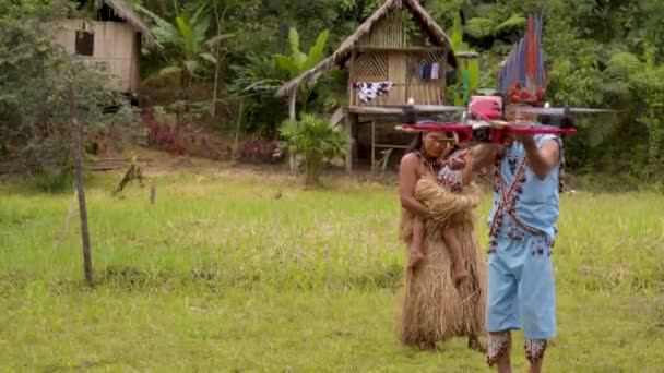 先住民族の男は彼の村を飛んでいるドローンを撮影しています - 映像、動画