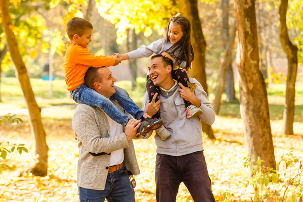 Szczęśliwi ojcowie i dzieci bawią się na świeżym powietrzu w ogrodzie sadowym, bawiąc się razem - Zdjęcie, obraz