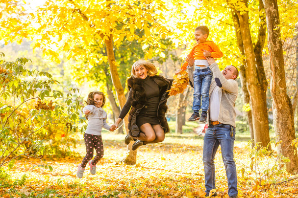 Rodzina z dwójką dzieci w jesiennym parku  - Zdjęcie, obraz