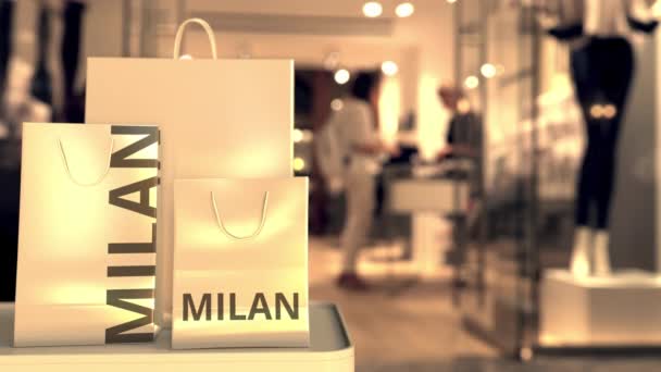 Paper shopping bags with MILAN text against blurred store. Italian shopping related clip - Materiał filmowy, wideo