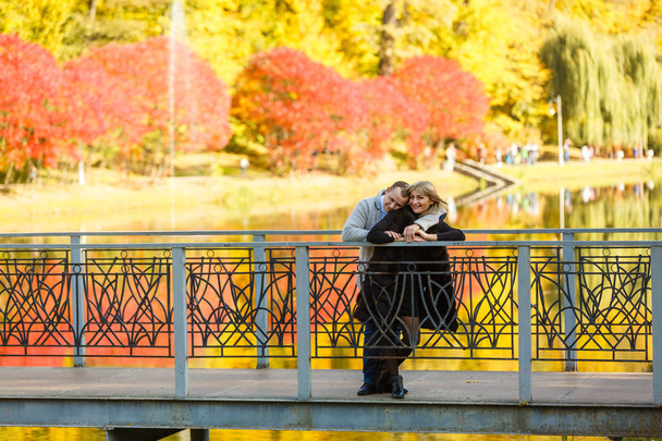 Νεαρή γυναίκα και άνδρας περπατούν στο πάρκο της πόλης το φθινόπωρο  - Φωτογραφία, εικόνα