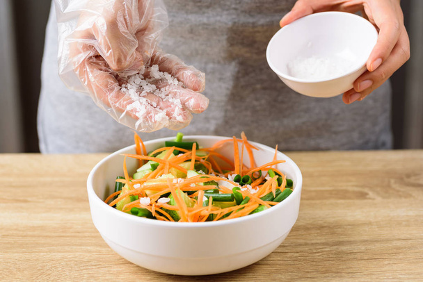 Kimchi pepino cozinhar passo 4, derramando sal e mistura com cebolinha fatiada, cenoura e pepino juntos em uma tigela
 - Foto, Imagem